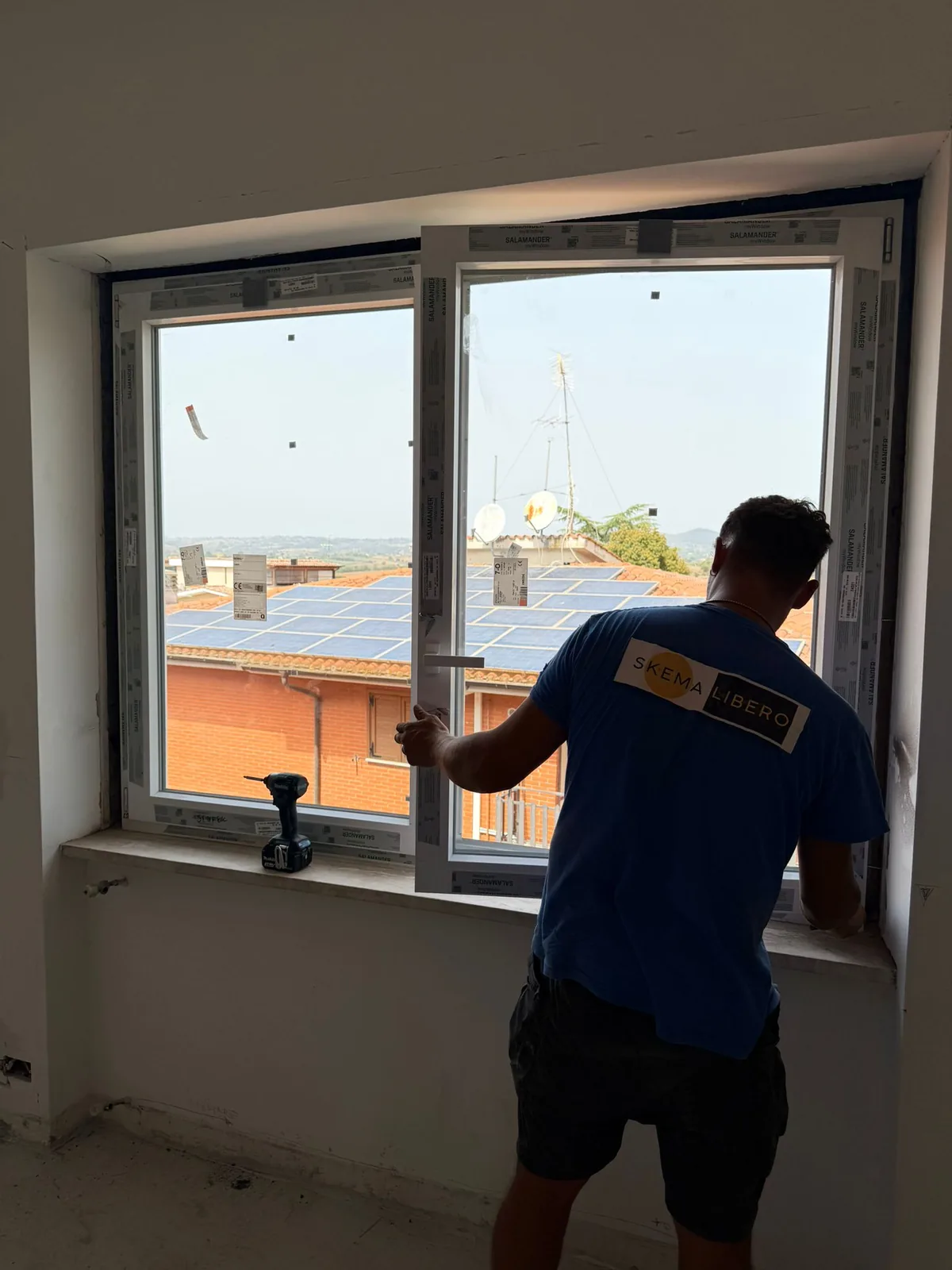 Installatore prova l'anta di una finestra in PVC bianco a due ante, pellicole protettive ancora sui profili