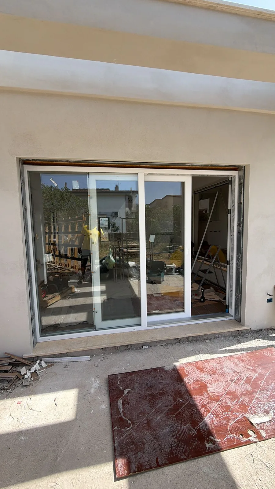Portafinestra scorrevole in PVC bianco a due ante vista dall'esterno, con soglia in pietra