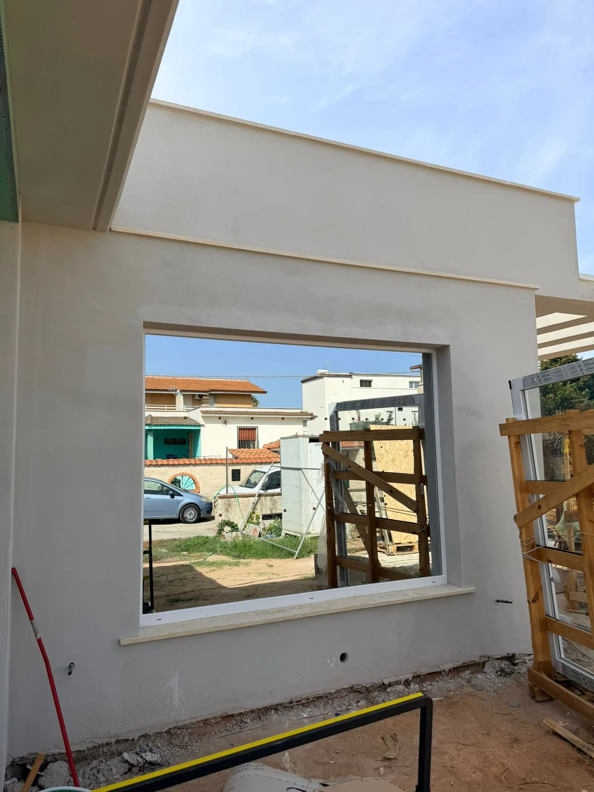 Vetrata fissa posata con davanzale in pietra e serramenti imballati sui cavalletti accanto