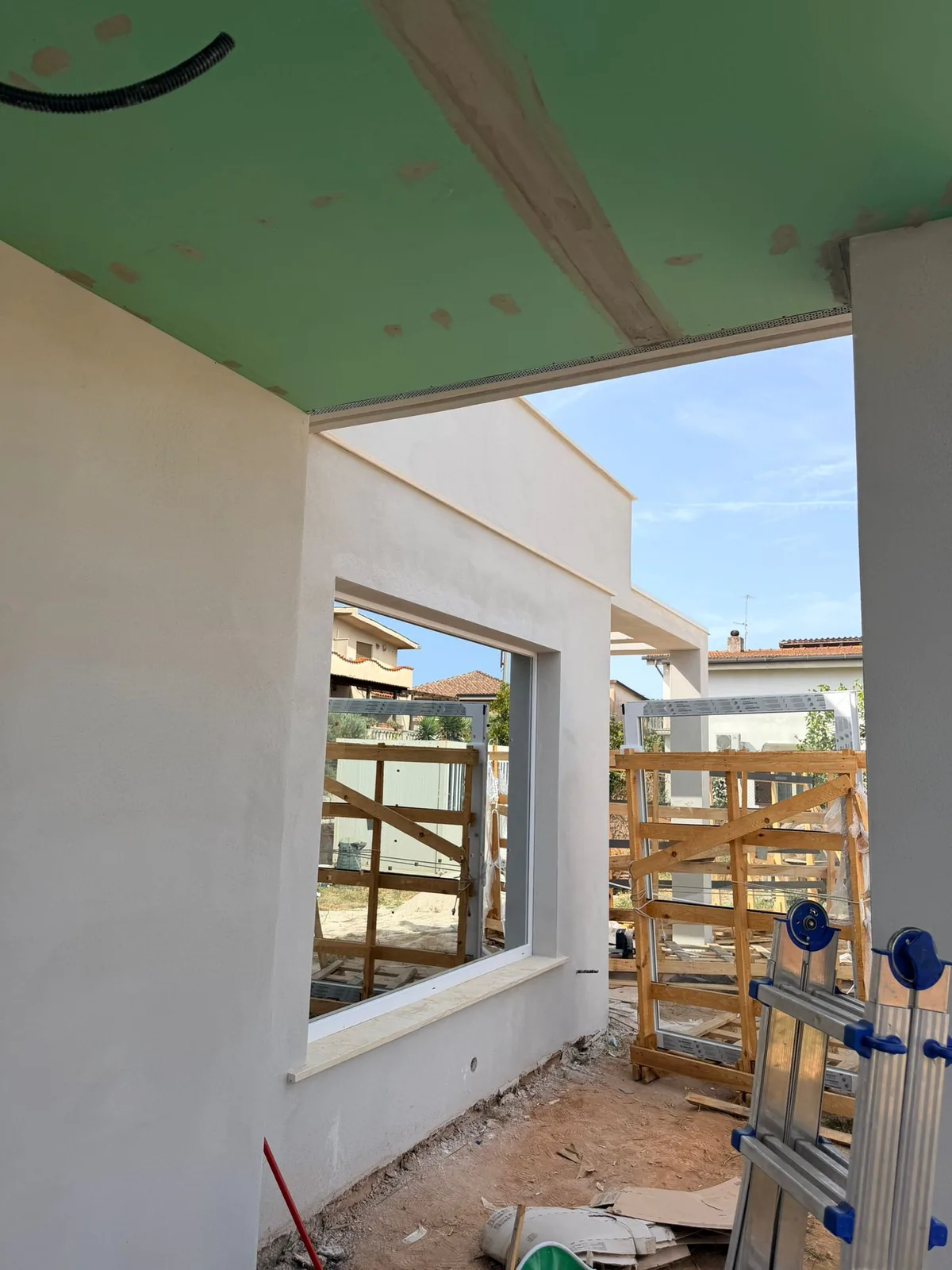 Portico in costruzione con vetrata fissa a telaio grigio posata e serramenti sui cavalletti