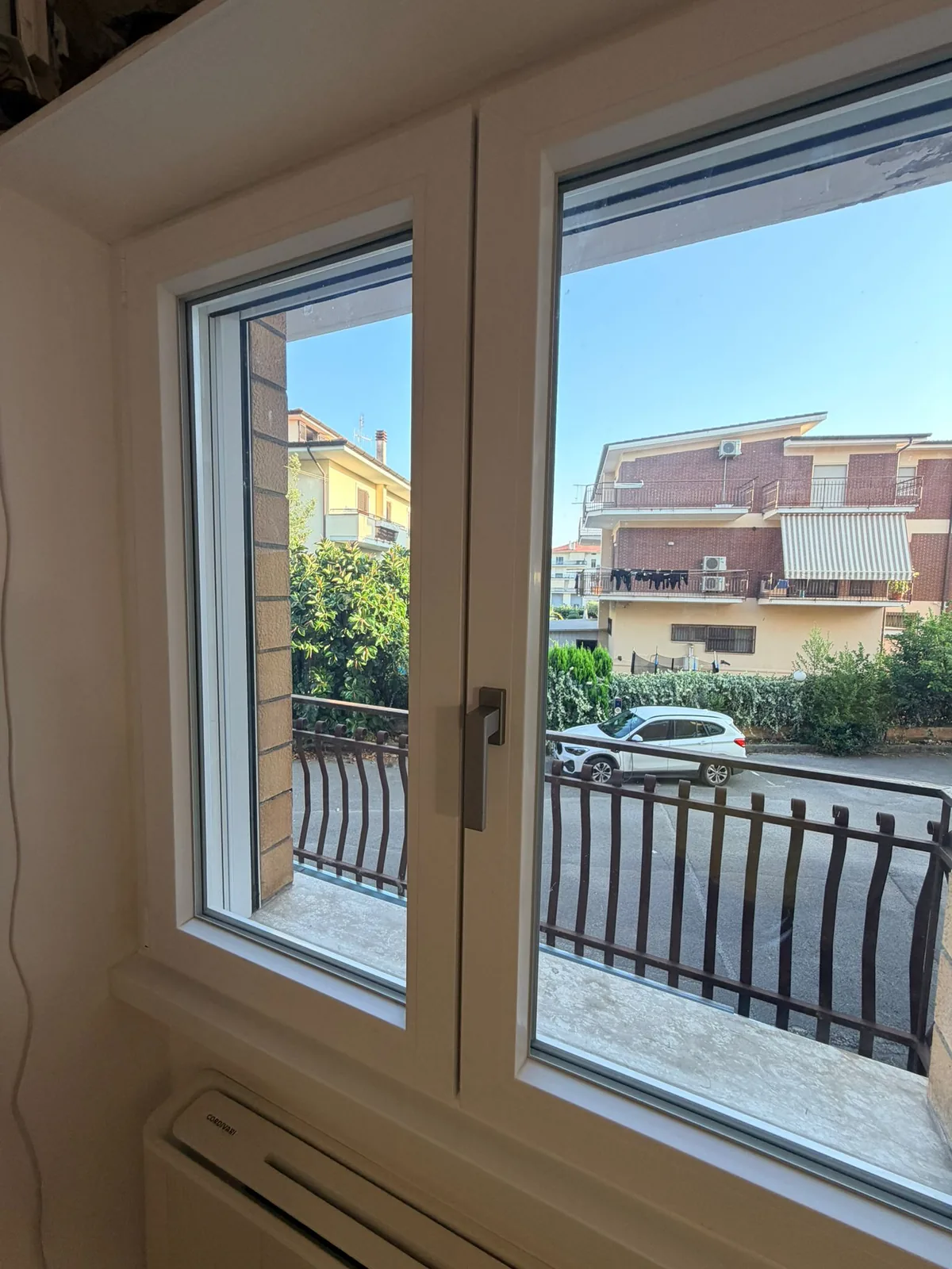 Finestra a due ante bianca con maniglia brunita e davanzale in pietra, vista dall'interno