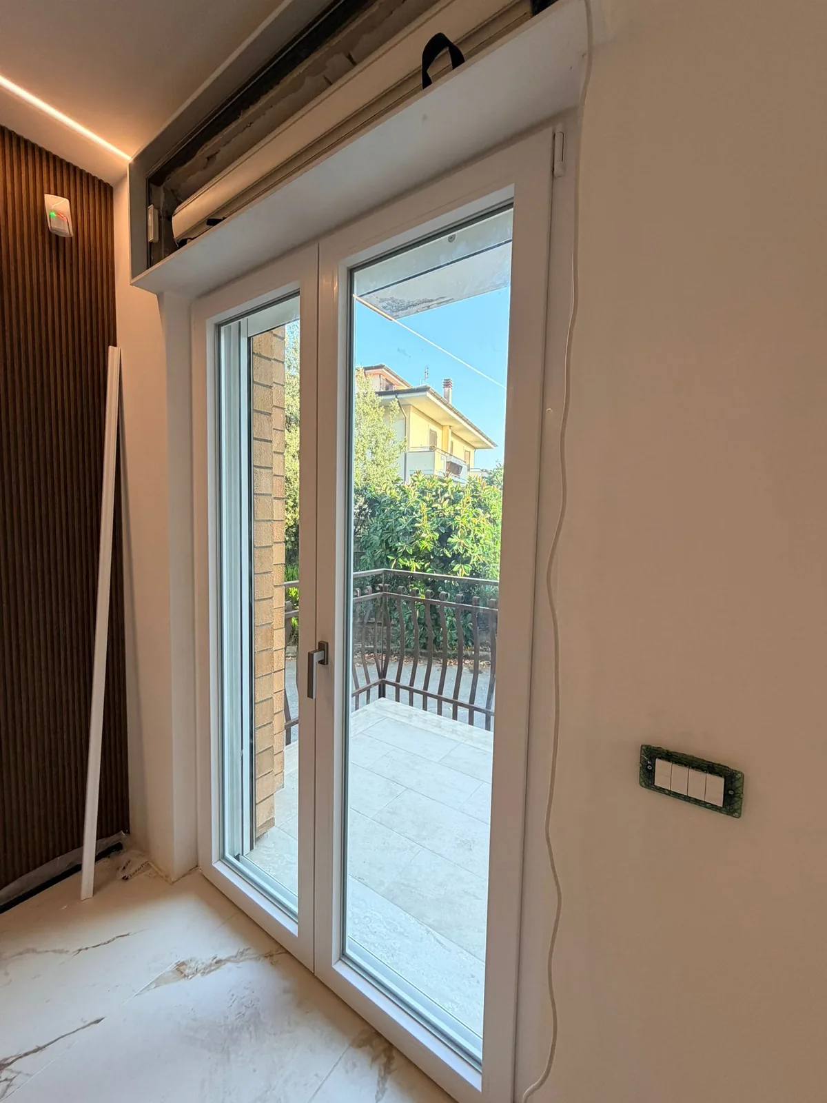 Portafinestra bianca a due ante vista dall'interno, con il cassonetto sopra ancora aperto