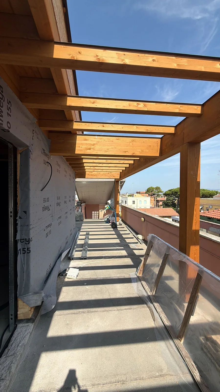 Sequenza di travetti in legno lamellare di una copertura in costruzione lungo un terrazzo