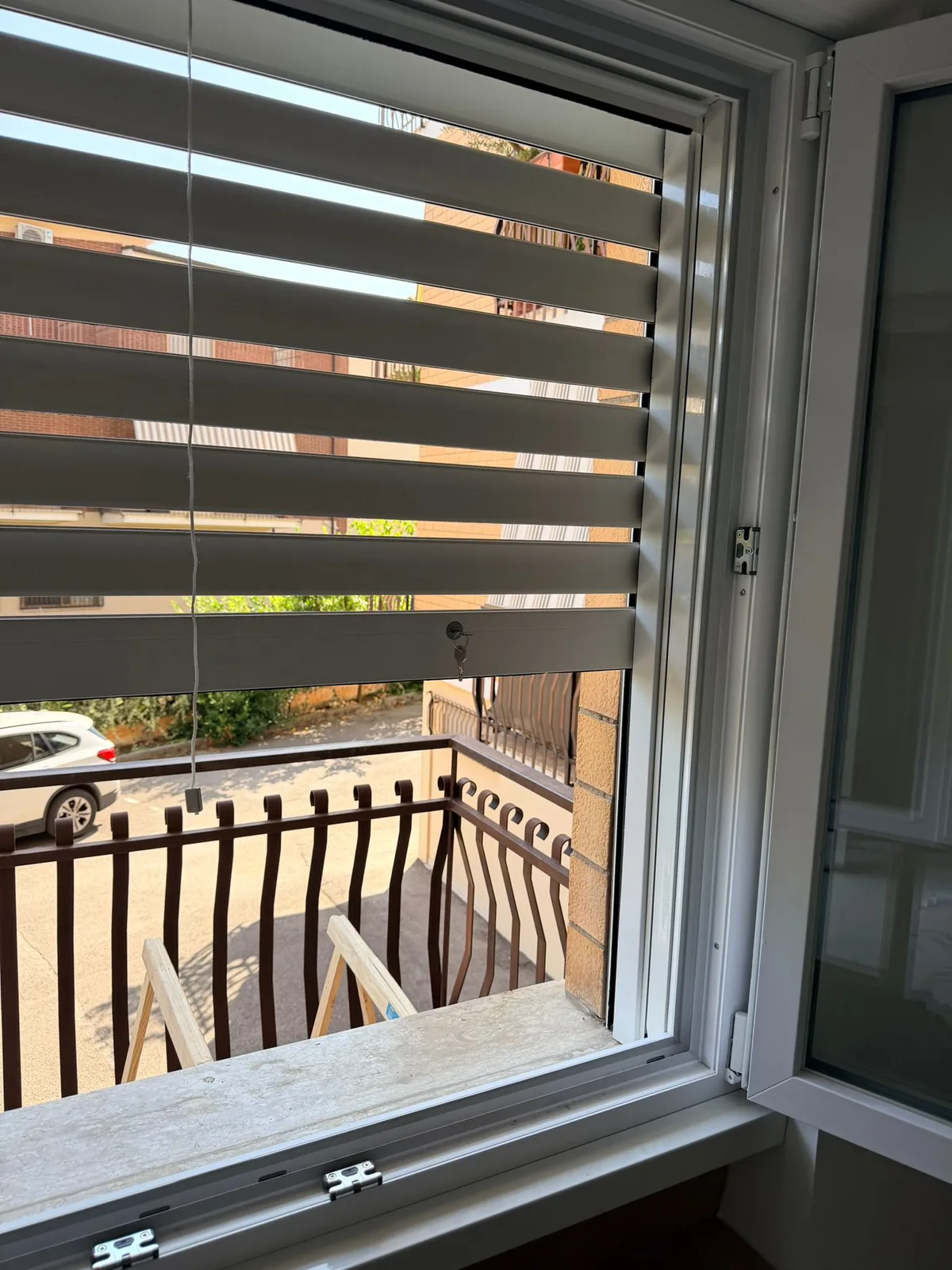 Tapparella blindata a lamelle orientabili vista dall'interno, con serratura a chiave e finestra in PVC bianco aperta
