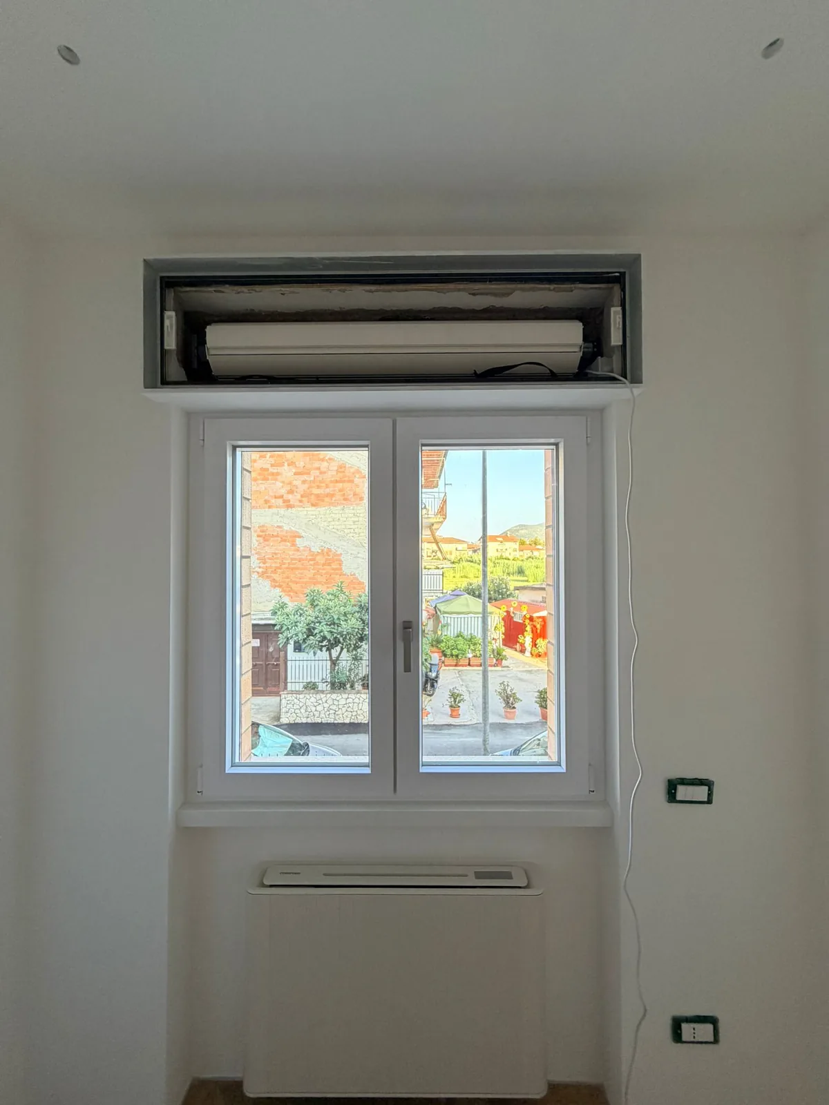 Finestra in PVC bianco a due ante con il cassonetto aperto sul rullo motorizzato della tapparella