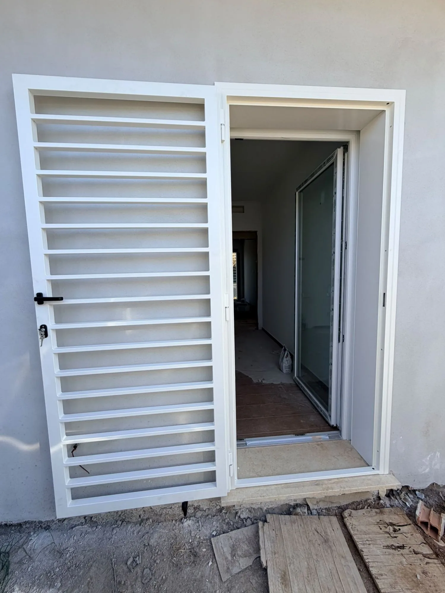 Grata di sicurezza bianca a barre orizzontali aperta su una portafinestra in PVC bianco di una casa in costruzione