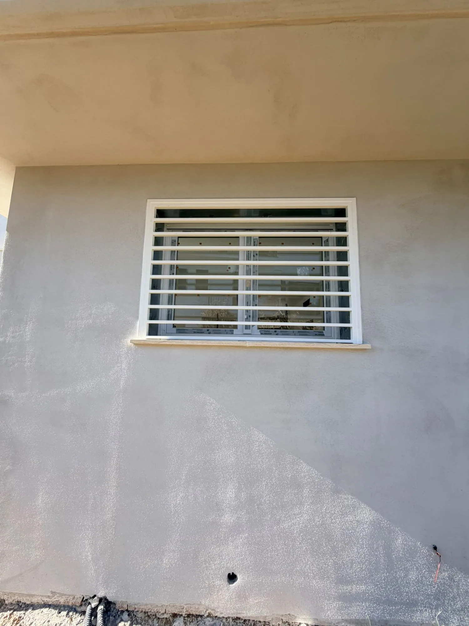 Grata di sicurezza bianca a barre orizzontali su finestra in PVC bianco con pellicole Salamander, davanzale in marmo