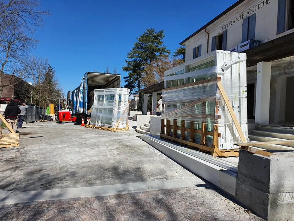 Casse di serramenti imballati sul piazzale di un ristorante in ristrutturazione, camion con portellone aperto