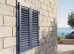 Persiane su un muro in pietra chiara, con vista sul mare
