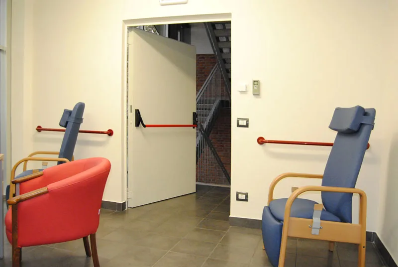 Porta metallica a un'anta aperta, con maniglione antipanico, che dà su una scala di sicurezza esterna in acciaio.