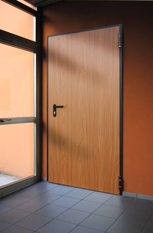 Porta a un'anta rivestita effetto legno chiaro, con telaio scuro e maniglia nera, accanto a una vetrata.