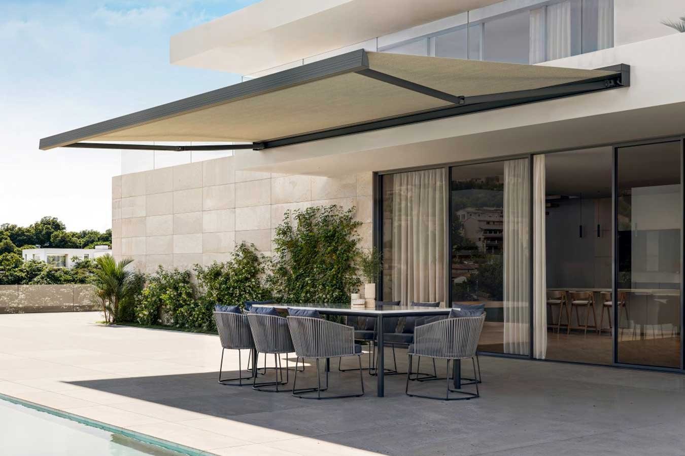 Tenda a bracci aperta sopra il tavolo da pranzo di un patio con piscina